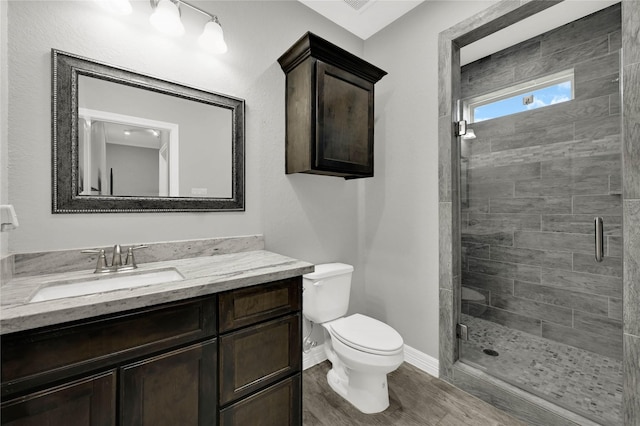 bathroom featuring vanity, a stall shower, wood finished floors, and toilet