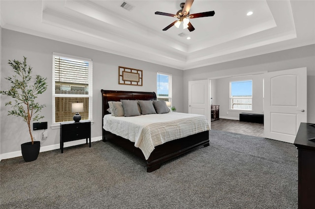 bedroom with a raised ceiling, visible vents, and baseboards