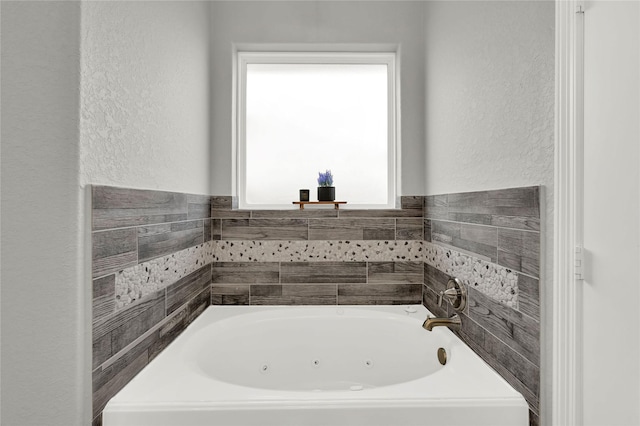 full bathroom featuring a textured wall and a tub with jets