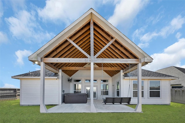 rear view of house with a patio, a yard, fence, and a hot tub