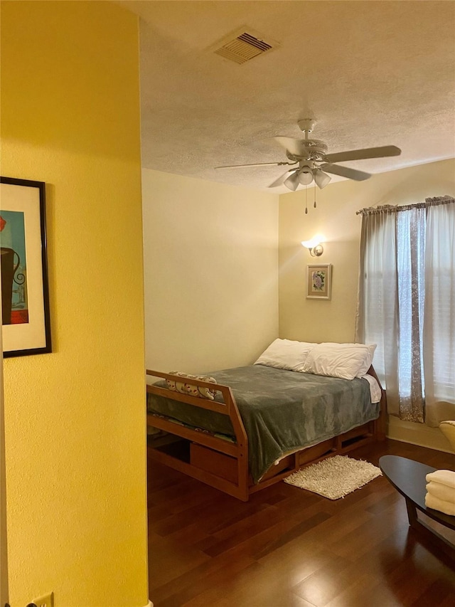 bedroom featuring ceiling fan, wood-type flooring, and a textured ceiling