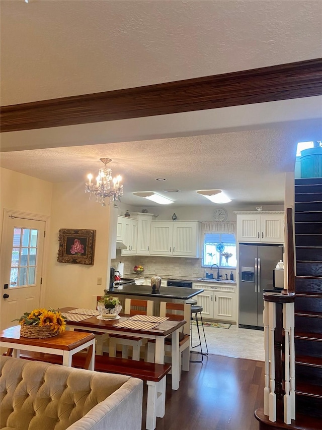 kitchen featuring stainless steel refrigerator with ice dispenser, white cabinetry, a chandelier, dark hardwood / wood-style floors, and decorative backsplash