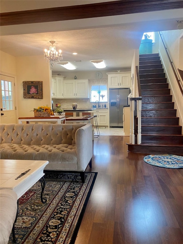 living room featuring an inviting chandelier, sink, hardwood / wood-style floors, and a textured ceiling