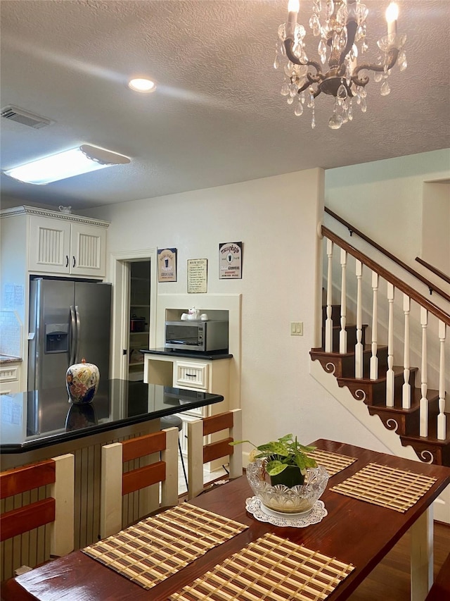 kitchen with white cabinetry, stainless steel appliances, a textured ceiling, and a notable chandelier