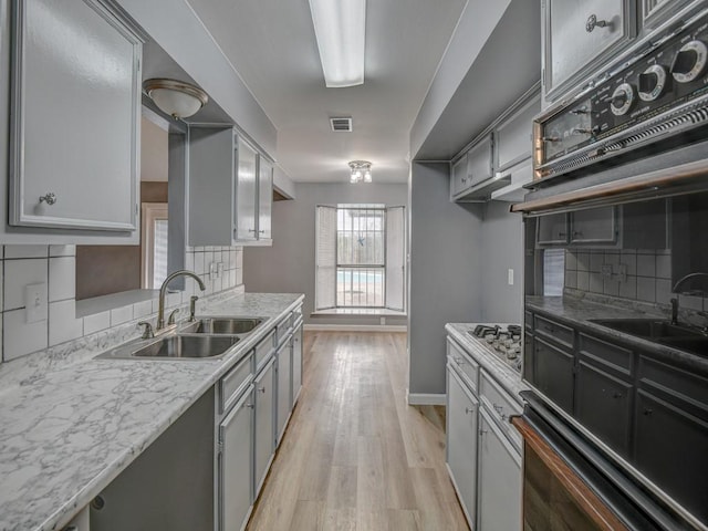 kitchen featuring gray cabinetry, sink, and backsplash