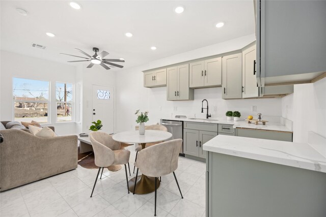 kitchen with sink, gray cabinets, dishwasher, ceiling fan, and light stone counters