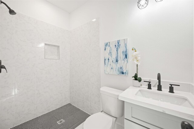 bathroom featuring vanity, toilet, and a tile shower