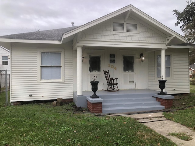 bungalow-style home featuring covered porch and a front lawn