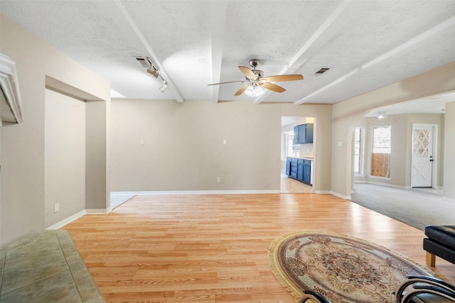 living room with ceiling fan, rail lighting, light hardwood / wood-style floors, and a textured ceiling