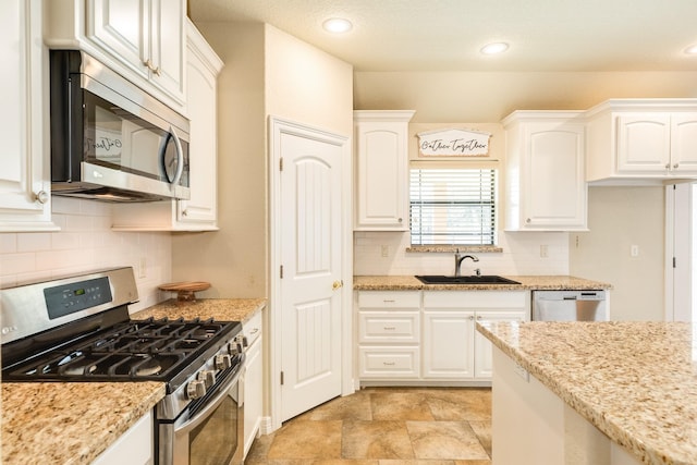 kitchen featuring sink, light stone countertops, white cabinets, and appliances with stainless steel finishes