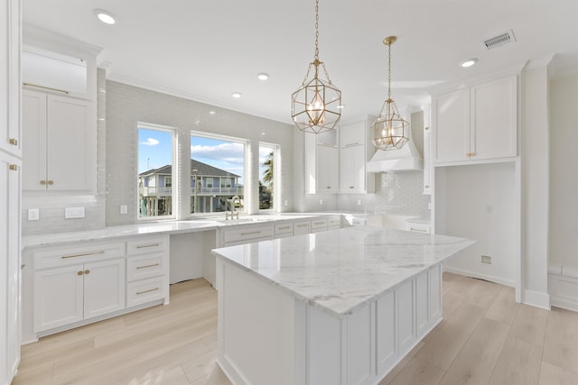23015 Lunes, Galveston, TX 77554 - kitchen with backsplash, a center island, light stone counters, light wood finished floors, and recessed lighting