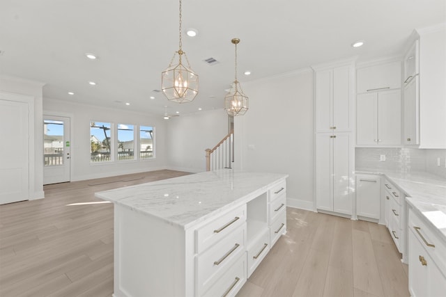 23015 Lunes, Galveston, TX 77554 - kitchen with light wood-style floors, recessed lighting, a kitchen island, ornamental molding, and light stone counters
