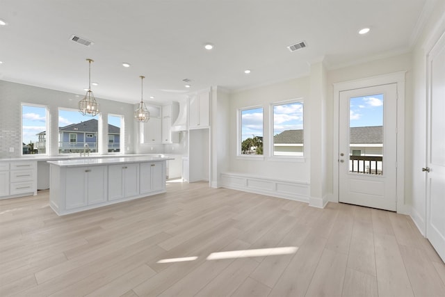 23015 Lunes, Galveston, TX 77554 - kitchen with plenty of natural light, white cabinetry, ornamental molding, light countertops, and light wood-type flooring