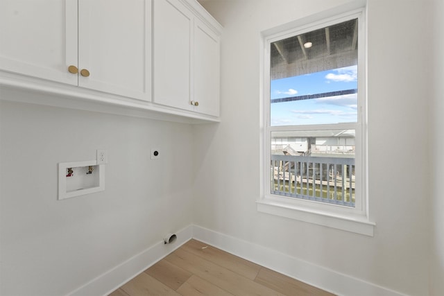 23015 Lunes, Galveston, TX 77554 - laundry area featuring cabinet space, hookup for an electric dryer, light wood-style flooring, washer hookup, and baseboards