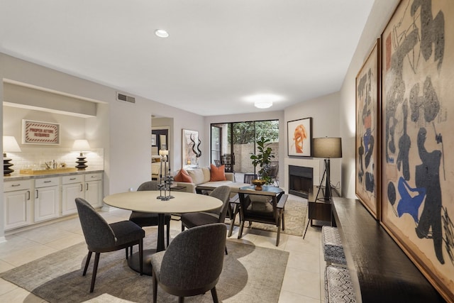 dining area with a tiled fireplace and light tile patterned floors