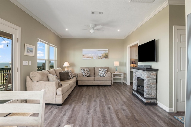 living room with ceiling fan, ornamental molding, a stone fireplace, and hardwood / wood-style floors