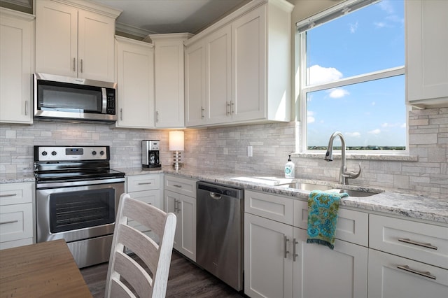 kitchen featuring sink, stainless steel appliances, light stone countertops, white cabinets, and decorative backsplash