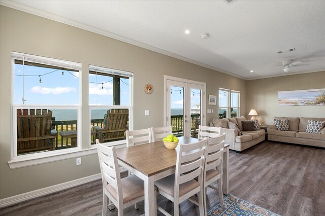 dining room with a water view, ceiling fan, ornamental molding, and dark hardwood / wood-style flooring