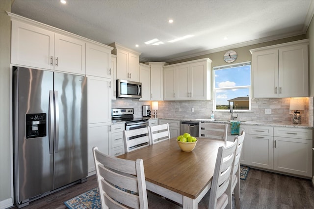 kitchen featuring dark wood-type flooring, appliances with stainless steel finishes, white cabinetry, tasteful backsplash, and light stone countertops