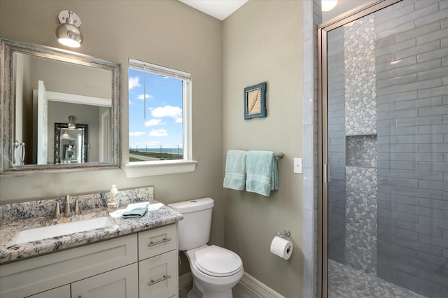 bathroom featuring a shower with door, vanity, and toilet