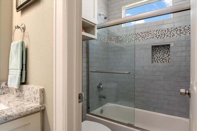 full bathroom featuring toilet, vanity, and shower / bath combination with glass door