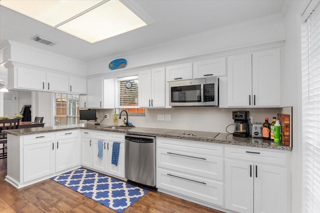 kitchen with sink, white cabinetry, stainless steel appliances, wood-type flooring, and kitchen peninsula