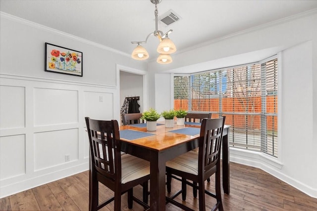 dining room with crown molding, an inviting chandelier, and hardwood / wood-style floors