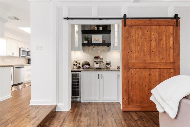 bar featuring white cabinetry, wine cooler, stainless steel appliances, and a barn door