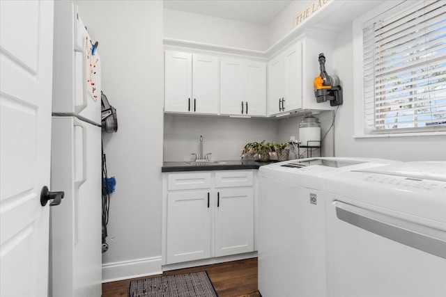 clothes washing area with cabinets, sink, dark wood-type flooring, and washing machine and clothes dryer