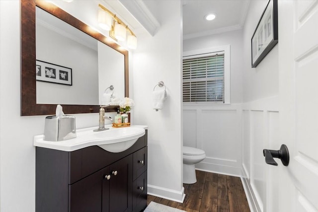 bathroom with hardwood / wood-style flooring, ornamental molding, vanity, and toilet