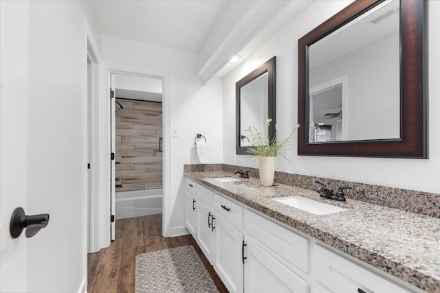 bathroom featuring vanity, wood-type flooring, and tiled shower / bath