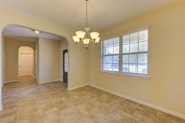 unfurnished room with a notable chandelier