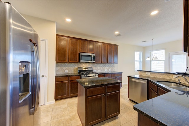 kitchen featuring sink, decorative light fixtures, appliances with stainless steel finishes, a kitchen island, and decorative backsplash