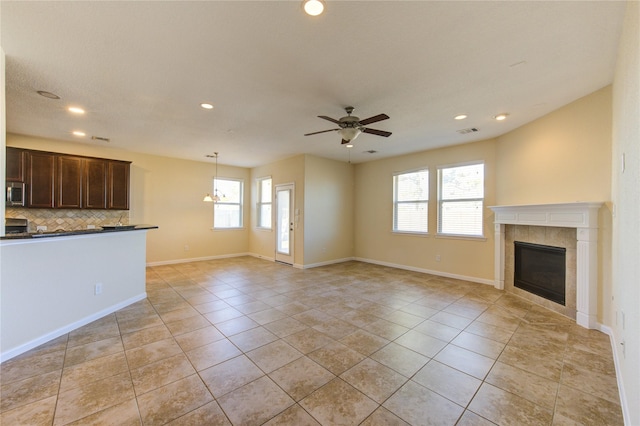 unfurnished living room with light tile patterned floors, a tile fireplace, and ceiling fan