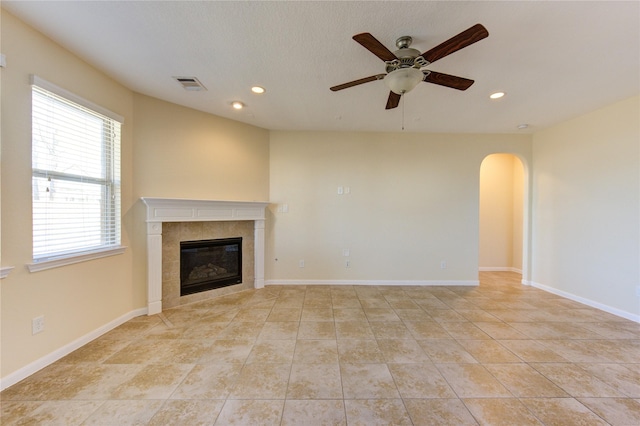 unfurnished living room featuring light tile patterned floors, a tile fireplace, and ceiling fan