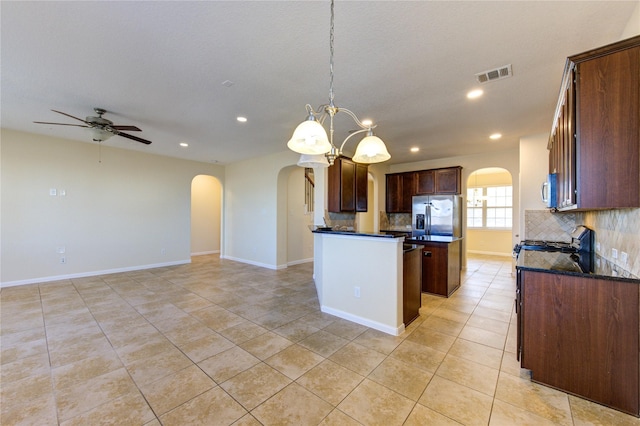 kitchen featuring tasteful backsplash, a center island, hanging light fixtures, light tile patterned floors, and appliances with stainless steel finishes