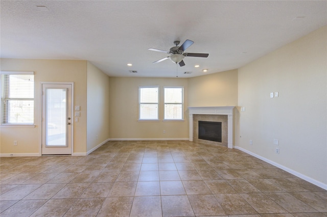 unfurnished living room with a tile fireplace, ceiling fan, and light tile patterned flooring