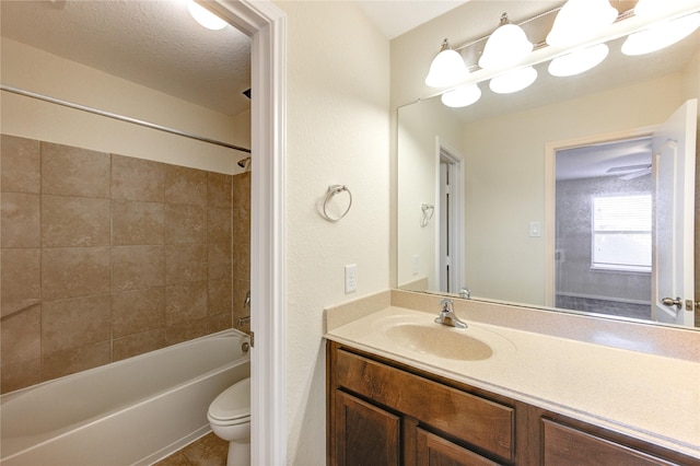 full bathroom with tiled shower / bath combo, vanity, toilet, tile patterned floors, and a textured ceiling