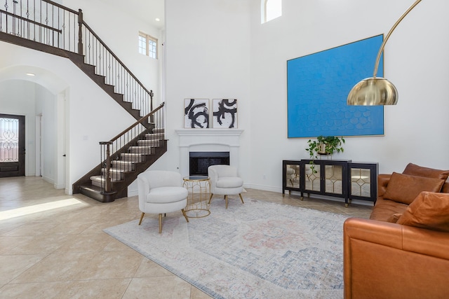 living room featuring a towering ceiling, light tile patterned floors, and a wealth of natural light