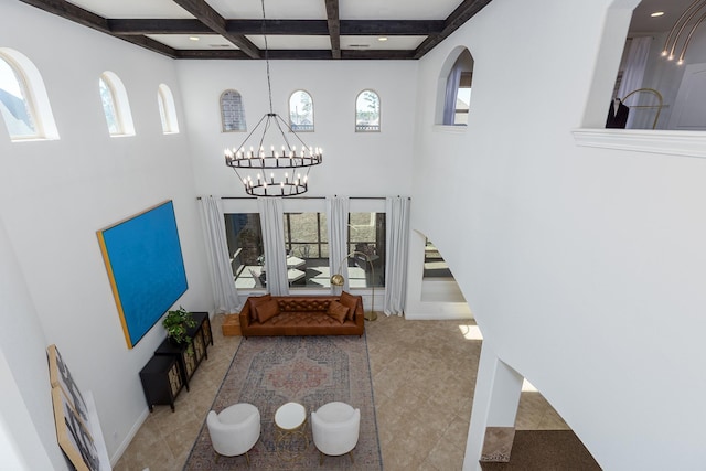 tiled living room with coffered ceiling, a notable chandelier, beamed ceiling, and a healthy amount of sunlight