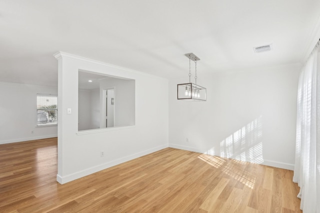 unfurnished dining area featuring an inviting chandelier, crown molding, and light hardwood / wood-style flooring