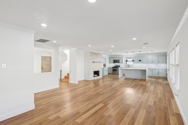 unfurnished living room with crown molding, a fireplace, and light hardwood / wood-style flooring