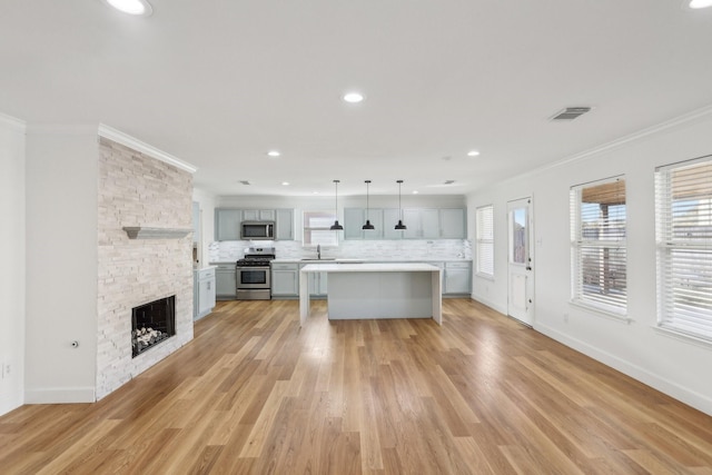 kitchen with gray cabinetry, stainless steel appliances, tasteful backsplash, a kitchen island, and decorative light fixtures