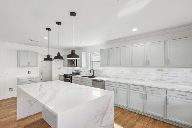 kitchen featuring a kitchen island, appliances with stainless steel finishes, decorative light fixtures, sink, and light hardwood / wood-style floors