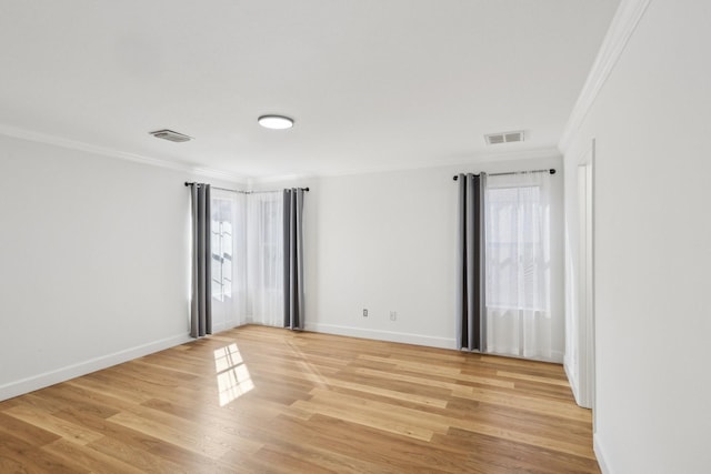 spare room featuring ornamental molding, light hardwood / wood-style floors, and a wealth of natural light