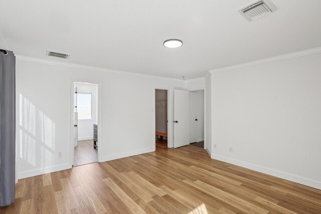 spare room featuring ornamental molding and light hardwood / wood-style flooring