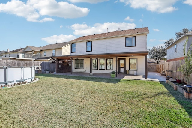 back of property with a yard, a fenced in pool, and a patio