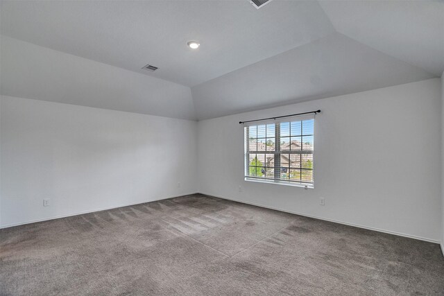 carpeted empty room with vaulted ceiling