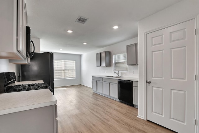 kitchen with light wood-type flooring, gray cabinetry, visible vents, and black appliances