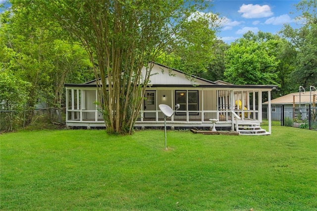 back of house with a sunroom and a lawn